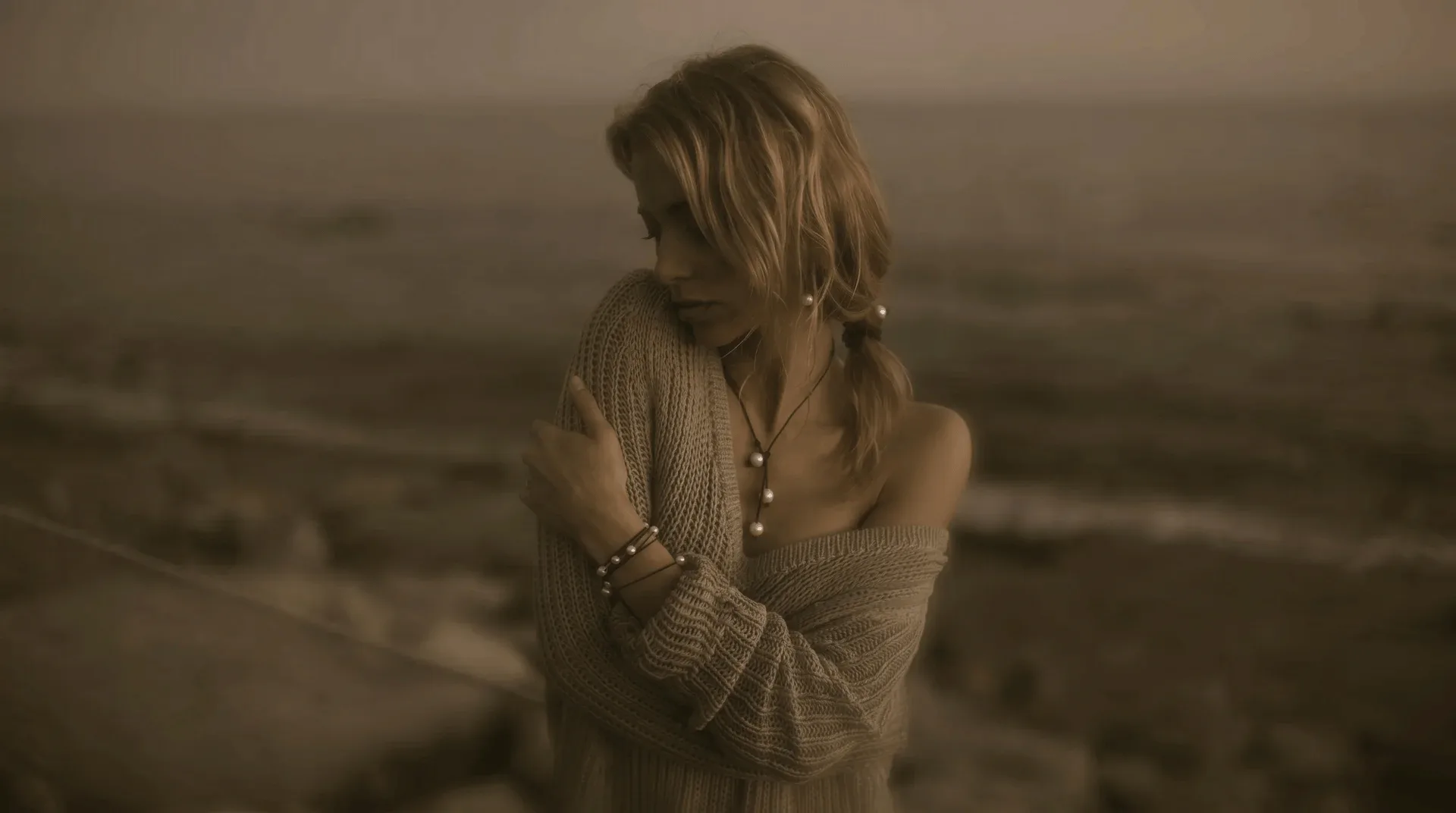 Model wearing Vincent Peach Tahitian pearl necklace and leather-and-pearl bracelet at golden hour